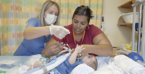nurses teaches mom to care for her infant on a ventilator