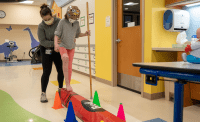 child and therapist on balance beam