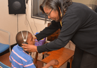 Young boy with headphones helped by woman in black sweater