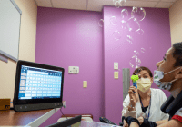 Child working on speech with bubbles and assistive communication device