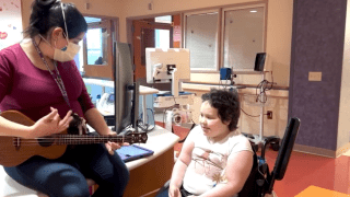 music therapist plays guitar for patient