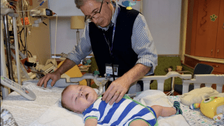 Doctor with baby at hospital bed