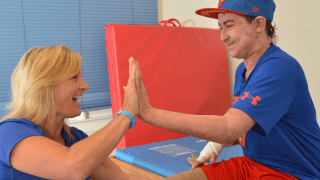 a therapist and a teenage boy high five during therapy