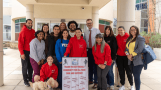 Group of people standing in front of hospital with sign