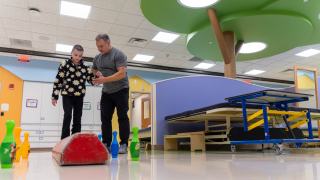 child and therapist working on balance beam