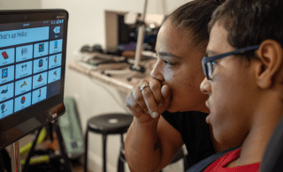 Mom and teenage son look at adaptive computer screen