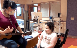 music therapist plays guitar for patient