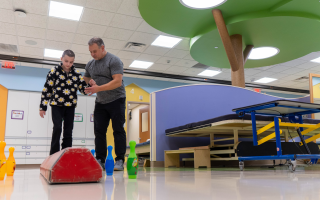 child and therapist working on balance beam