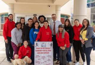 Group of people standing in front of hospital with sign
