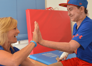 a therapist and a teenage boy high five during therapy