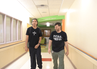 Patient walking down the hallway with physical therapist