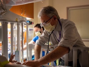 Doctor checking infant in crib