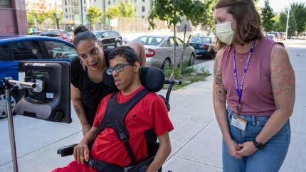 teen boy in adaptive wheelchair on street in city with mother and case manager