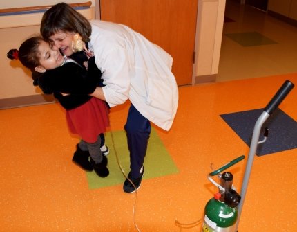 child with respiratory therapist hugging her