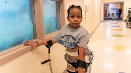 photo of child using a wall to prop himself up