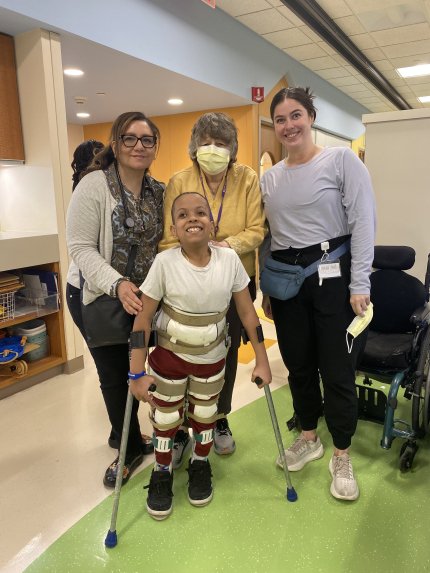 child poses for photo with therapy team