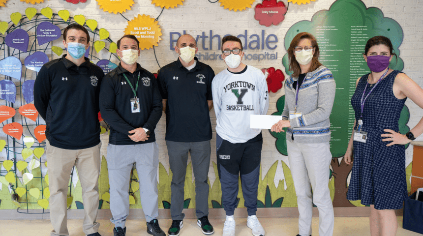teen basketbal player and teammates present check to hospital staff