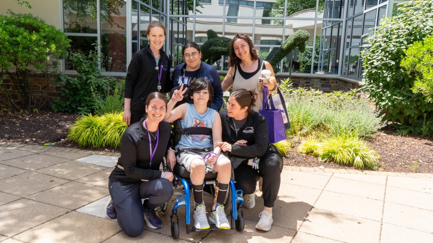 child in a wheelchair surrounded by staff